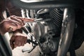 Man`s hands fixing motorcycle indoors