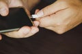 Close up a man`s hands using a USB type C cable to charge a mobile phone on a wooden table Royalty Free Stock Photo