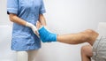 Female doctor in a blue medical gown checking broken leg on male patient Royalty Free Stock Photo