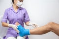 Female doctor in a blue medical gown checking broken leg on male patient Royalty Free Stock Photo