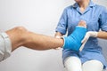 Female doctor in a blue medical gown checking broken leg on male patient Royalty Free Stock Photo