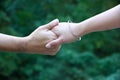 A close up of a man\'s and a woman\'s hands holding each other. The woman is wearing a bracelet