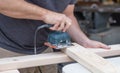 A man working on a home improvement project sanding wood with an electrical sander.