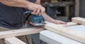 A man working on a home improvement project sanding wood with an electrical sander.