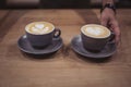 Close up of man serving coffee while standing in coffee shop. Focus on a cups of coffee on counter.