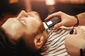 Close up Man is shaved in barbershop with electric razor. Hands of hairdresser frame holding tool. Royalty Free Stock Photo