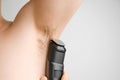 Close up man shaves hairy armpits with an electric razor. Unshaved armpits or underarm. Depilation and hair remove procedure using Royalty Free Stock Photo