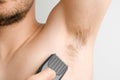 Close up man shaves hairy armpits with an electric razor. Unshaved armpits or underarm. Depilation and hair remove procedure using Royalty Free Stock Photo