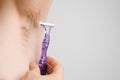 Close up man shaves hairy armpits with a purple razor. Unshaved armpits or underarm. Depilation and hair remove Royalty Free Stock Photo