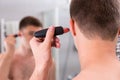 Close up man shaving his ear with trimmer in the bathroom