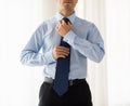 Close up of man in shirt adjusting tie on neck Royalty Free Stock Photo