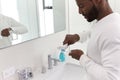 Close Up Of Man Squeezing Toothpaste Onto Toothbrush In Bathroom