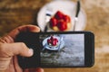 Close up of man taking picture of a little strawberry cake to share on social media and receive likes and followers. People and