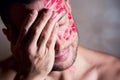 Close-up of a man with traces of lipstick on his face, which covers his face with his palm