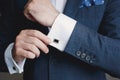 Close-up of a man in a tux fixing his cufflink.