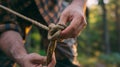 Close-up of a man tying a knot in a rope in a forest, AI-generated.