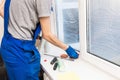 Close-up of a man in uniform and blue gloves washes a windows with window scraper. Professional home cleaning service Royalty Free Stock Photo