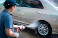 Close up of a man in uniform washes his car with a large head of water from a karcher and washing car with soap. Cleaning and Royalty Free Stock Photo