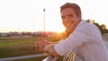 CLOSE UP: Man unwinding by looking around scenic sunlit nature smiles for camera