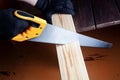 Close up the man use hand saw cutting wood board in the carpenter shop. Royalty Free Stock Photo