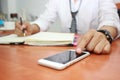 Close up of man using mobile smart phone and working on table in office Royalty Free Stock Photo