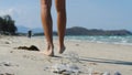 Close up of a man walking at the beach stepping on the plastics on the sand.