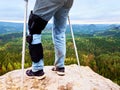 Man Walking With Crutches in nature. Man legs in jeans with adjustable Bandage on pain knee.