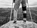 Man Walking With Crutches in nature. Man legs in jeans with adjustable Bandage on pain knee.