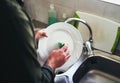 Close-up of a man washing the ceramic dish in the kitchen sink Royalty Free Stock Photo