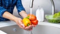 Close-up of man washing vegetables in kitchen sink with water.