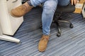 Close up man wear blue jeans and brown leather shoes sit and cross his legs on office chair