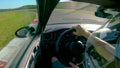 CLOSE UP: Man wearing a helmet races his fast car along the fun racetrack.