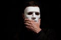 Close-up of a man in a white mask, surprise, thoughtfulness. Touches a hand to the mask Royalty Free Stock Photo