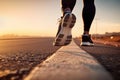 A close-up man or woman athlete feet jogging on road for workout in wellness concept at sunrise. Royalty Free Stock Photo