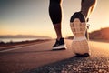 A close-up man or woman athlete feet jogging on road for workout in wellness concept at sunrise. Royalty Free Stock Photo