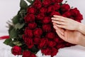 close-up of man and woman hands with engagement rings. Hands of the on the background of the big bouquet of red roses Royalty Free Stock Photo