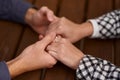 Close up on a man and a woman holding hands at a wooden table. Loving couple holding hands on table, man friend husband Royalty Free Stock Photo