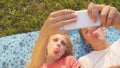 CLOSE UP: Man and woman making funny facial expressions while taking selfies. Royalty Free Stock Photo