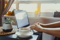 Close up man working on laptop sitting near coffee table with cup of hot drink tea. Workplace near window on sutset or early Royalty Free Stock Photo