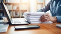 Close-up of a man working with a stack of documents and reports on his office desk. AI generated