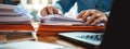 Close-up of a man working with a stack of documents and reports on his office desk. AI generated