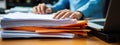 Close-up of a man working with a stack of documents and reports on his office desk. AI generated