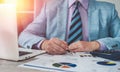 close-up of a man& x27;s hand checking accounting figures on a chart at an office desk.