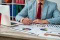 close-up of a man& x27;s hand checking accounting figures on a chart at an office desk.