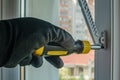 Close-up of a man's hand in a construction glove tightens a screw that fixes a plastic window opening limiter