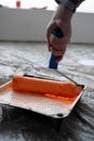 Close-up of a man& x27;s hand picking up paint with a roller from a plastic tray to paint a wall orange Royalty Free Stock Photo