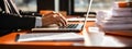 Close-up of a man& x27;s hands typing on a laptop keyboard, with a stack of paperwork beside them. AI generated Royalty Free Stock Photo