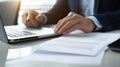Close-up of a man& x27;s hands typing on a laptop keyboard, with a stack of paperwork beside them. AI generated Royalty Free Stock Photo