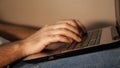 Close-up of a man& x27;s hands typing on a laptop that lies on his lap. Remote work at the laptop in the evening. Side Royalty Free Stock Photo