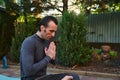 Close-up a man yogi, meditating in lotus pose on a fitness mat, keeping hands palms together, practicing yoga at sunset